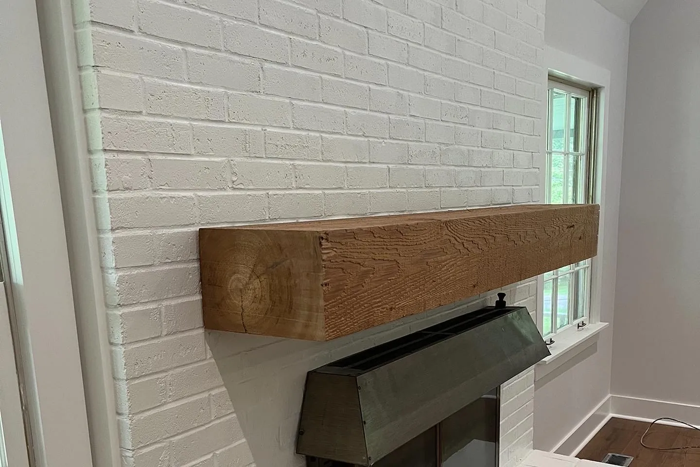 Painted brick fireplace with a rough-sawn wood mantel.